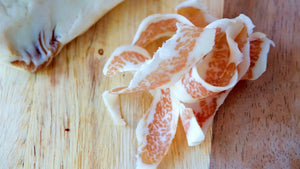 Thin slices of il porcellino salumi's Guanciale pictured from above on a cutting board.