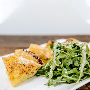il porcellino salumi's Frittata Du Jour displayed on a plate next to an arugula salad.