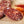 Load image into Gallery viewer, A close up of salami slices displaying the fat marbling, herbs and spices. The salami slices are on a wood cutting board with blurred herbs and spices in the background.
