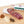 Load image into Gallery viewer, Cacciatore salami in packaging and cut into slices on a cutting board next to herbs and spices.
