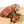 Load image into Gallery viewer, A chub of salami on a cutting board with half of it cut into bite size slices. Juniper berries and other herbs and spices are in the right foreground.
